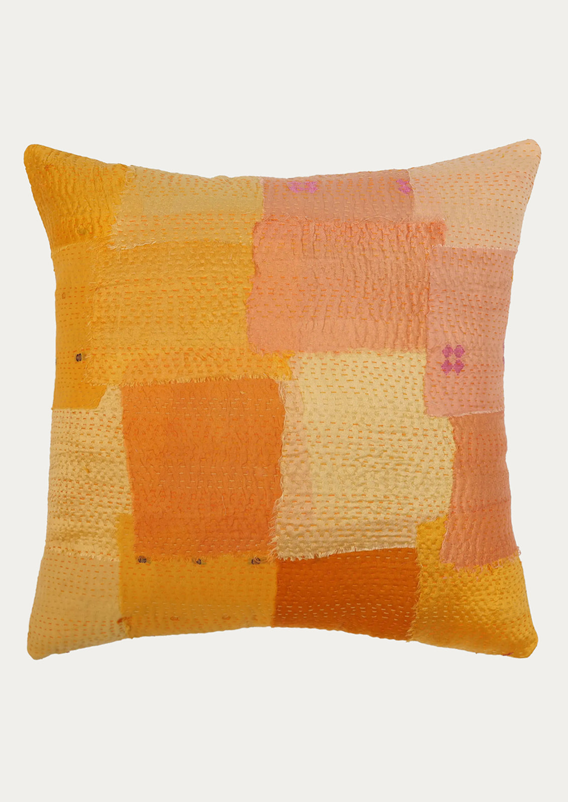 A square decorative throw pillow featuring a patchwork design of textured fabric blocks in shades of orange, yellow, peach, and cream, set against a plain light gray background.