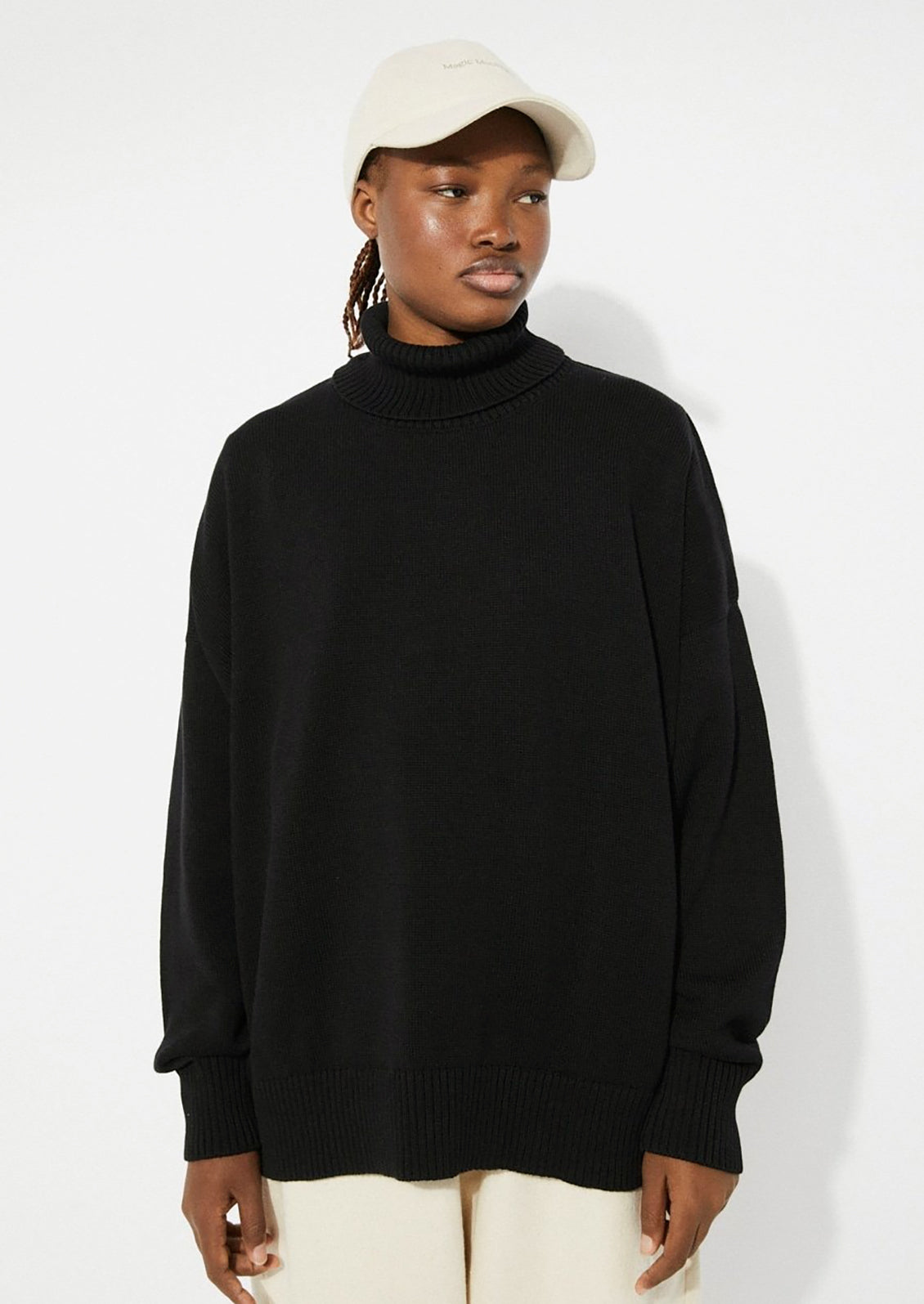 A woman wearing an oversized turtleneck sweater in black.