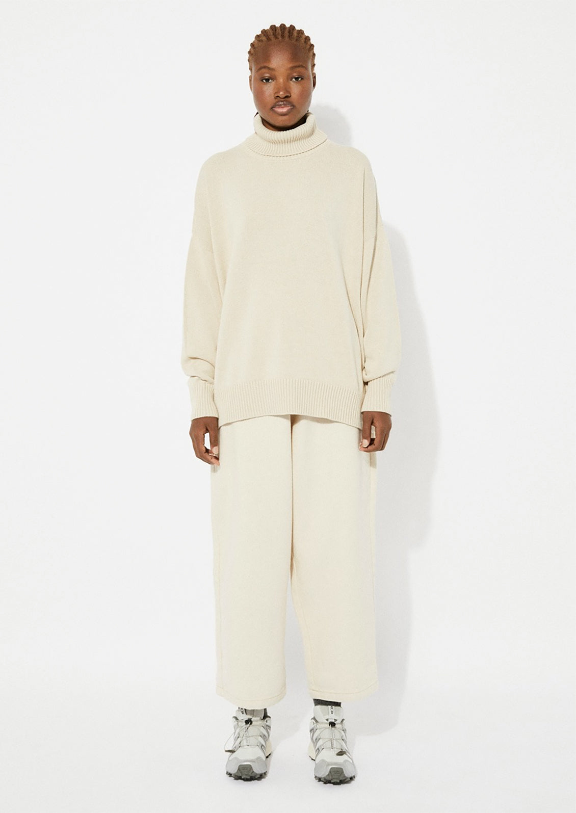A woman wearing an oversized turtleneck sweater in beige.
