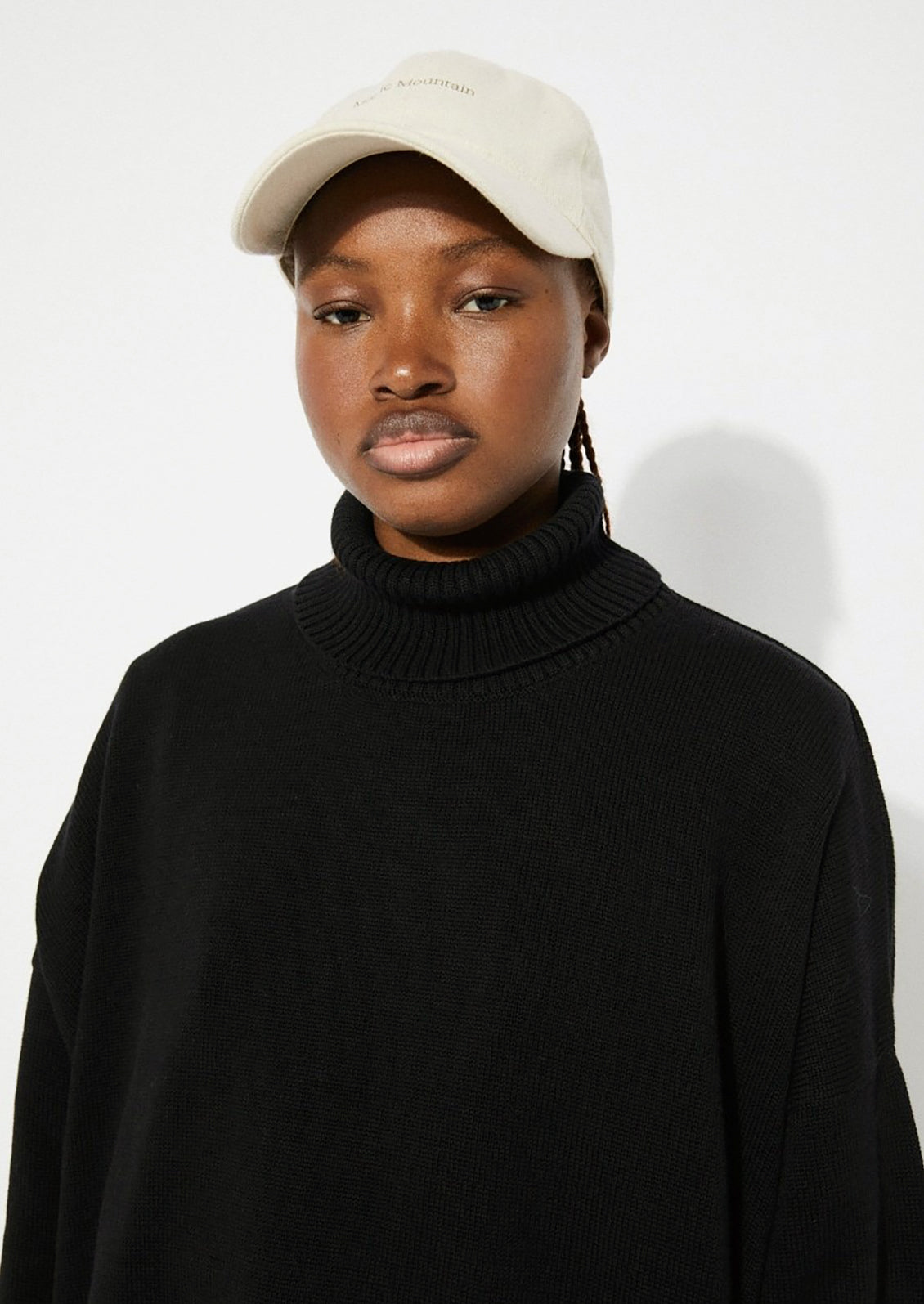 A woman wearing an oversized turtleneck sweater in black.