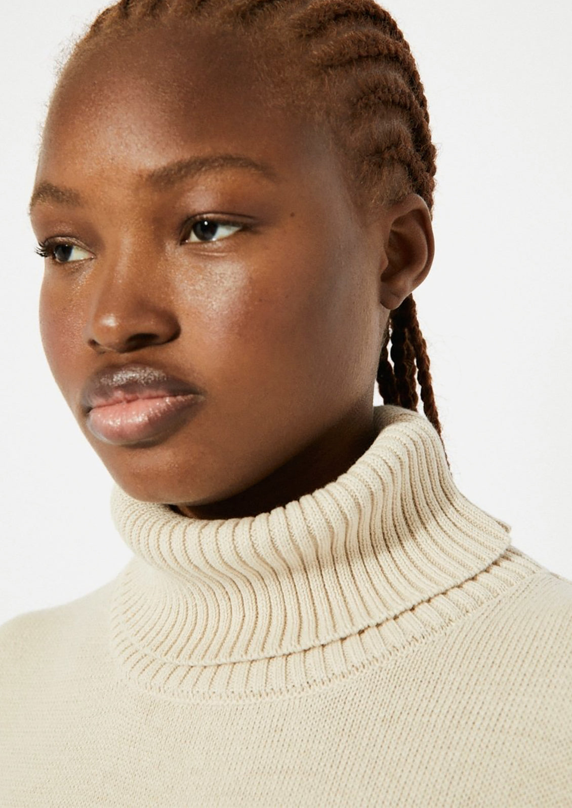 A woman wearing an oversized turtleneck sweater in beige.