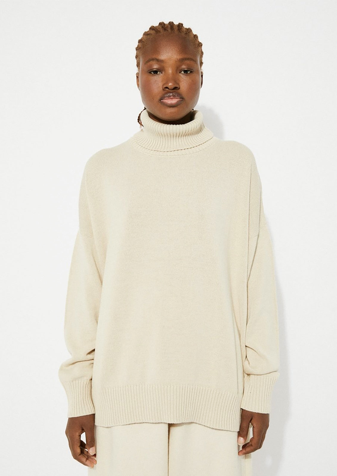 A woman wearing an oversized turtleneck sweater in beige.