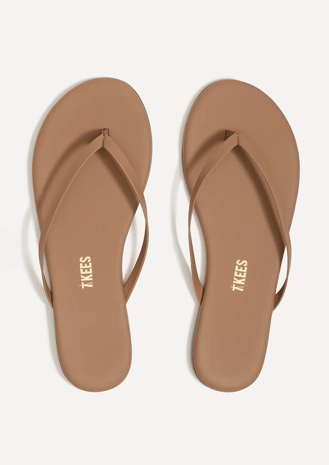 A pair of leather skinny strap TKEES sandals in nude.