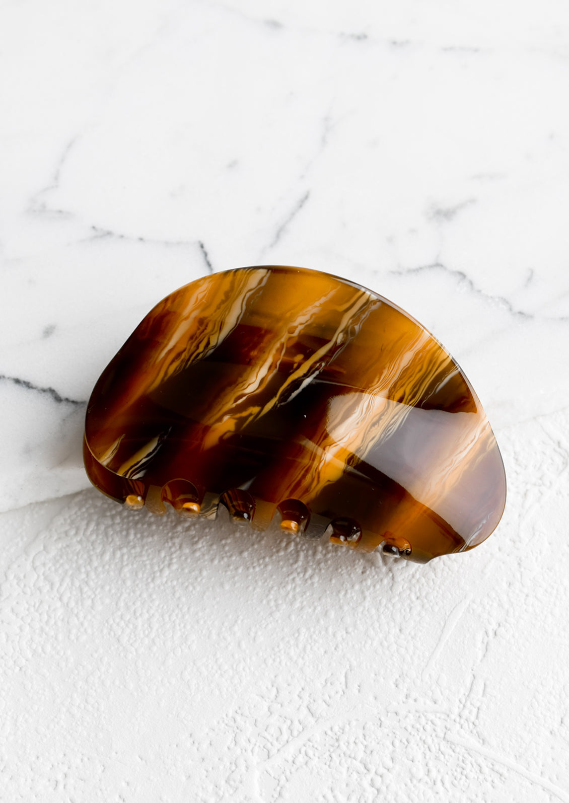 An asymmetric hair claw in marbled caramel.