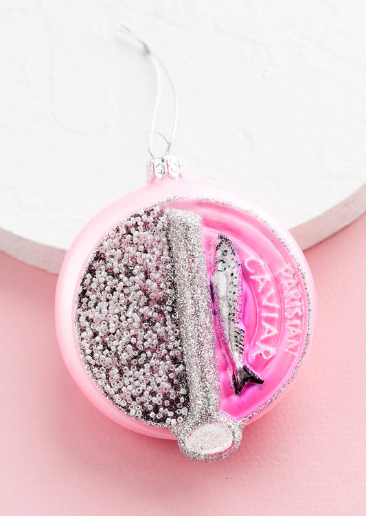 A glass ornament in the shape of round Parisian caviar tin.