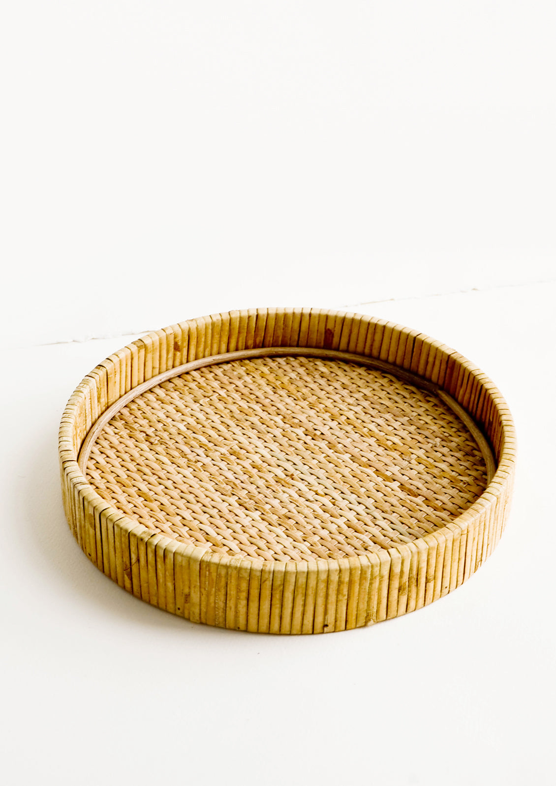 Round serving tray with raised rim, made from woven rattan