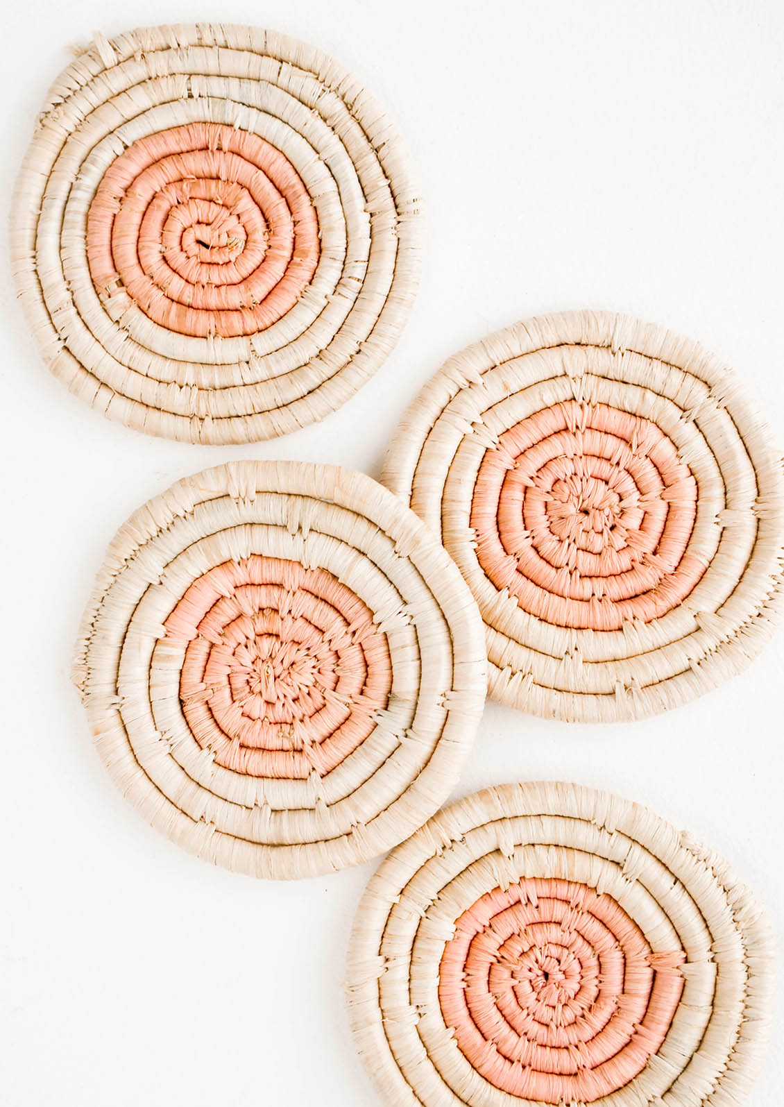 Set of four round raffia coasters with natural rim and pink colored center