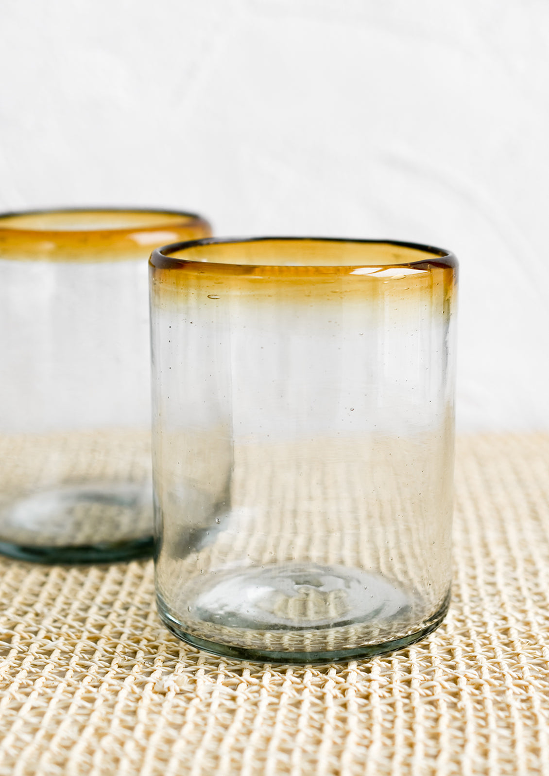 A heavy rocks glass in natural glass with amber rim around top.