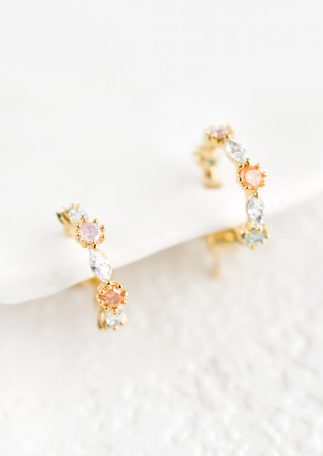 A small pair of huggie hoop earrings in pastel crystals.