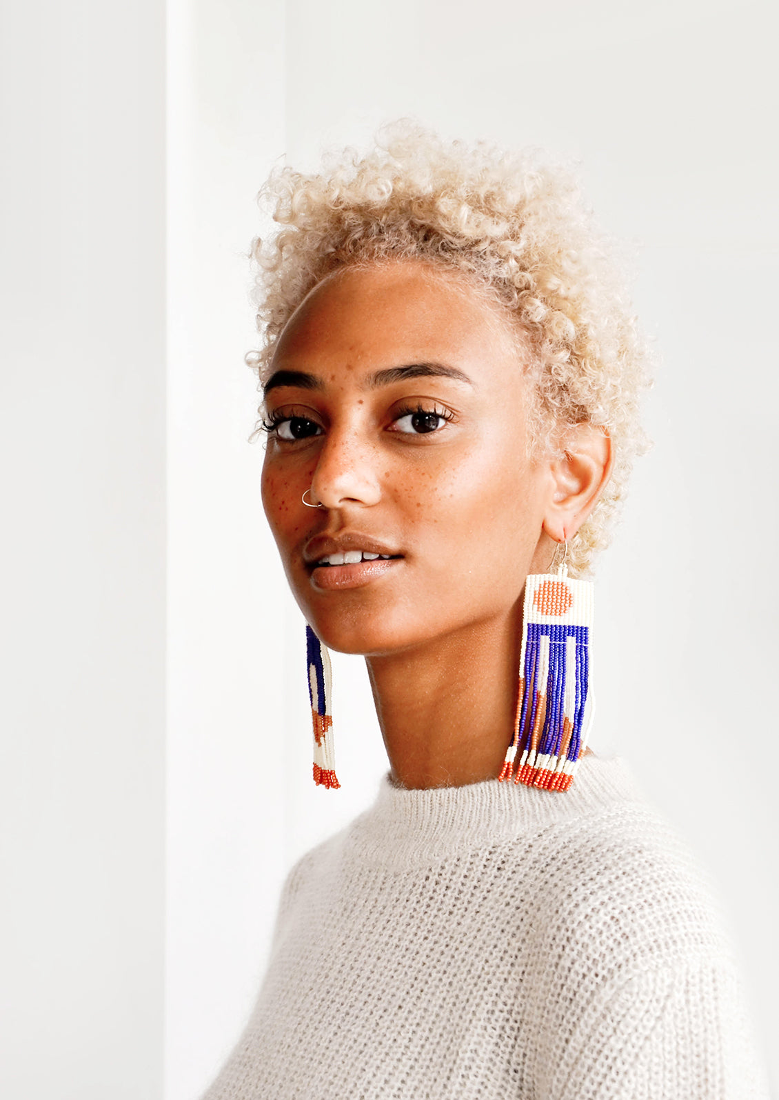 Model wears long fringe earrings with blue details. 