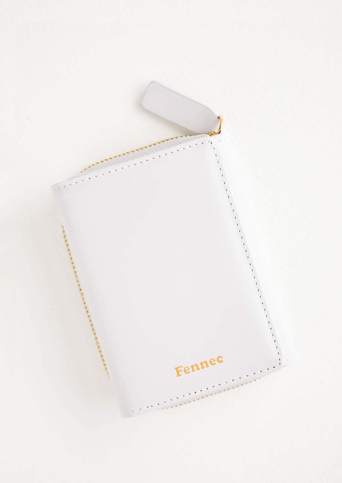 Light grey leather wallet that zips on three sides, in a closed position, with matching tab pull.