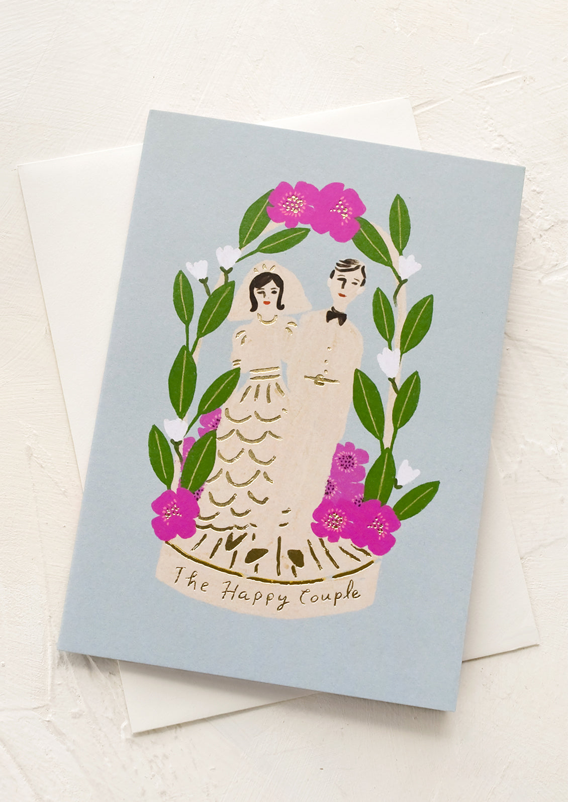 A blue greeting card with bride and groom, text reads "The happy couple".