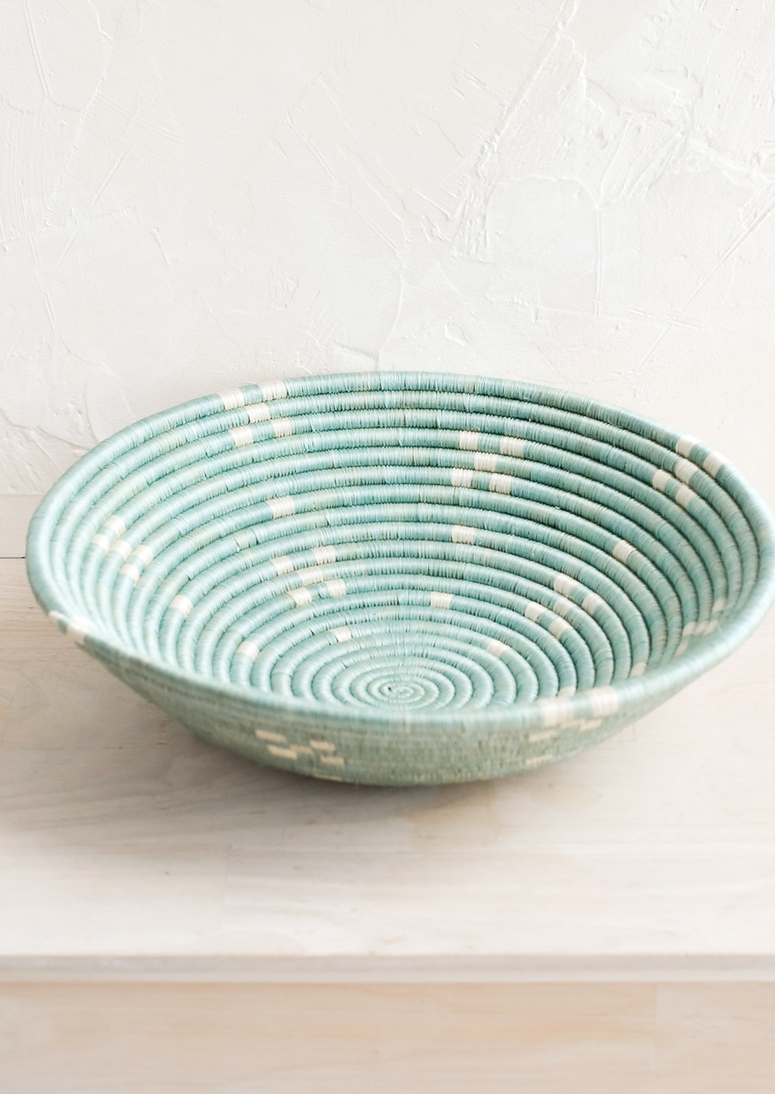 A round sweetgrass bowl in blue with white pattern.