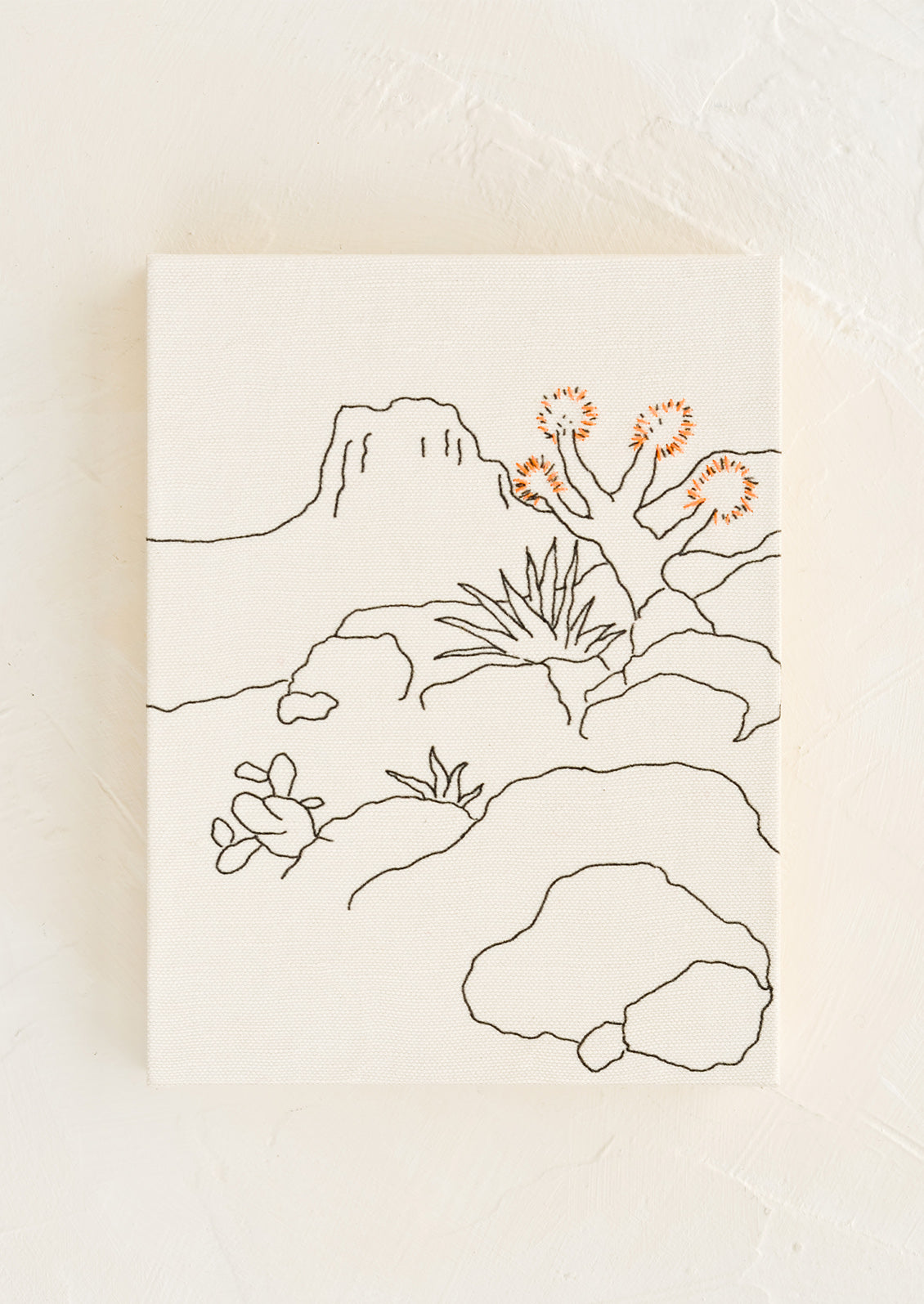 A white cloth covered journal with desert themed embroidery.