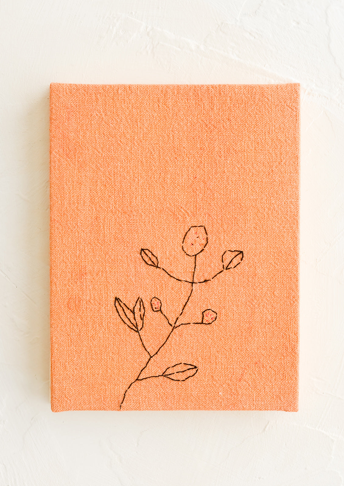 A peach cloth covered journal with botanical embroidery detail.