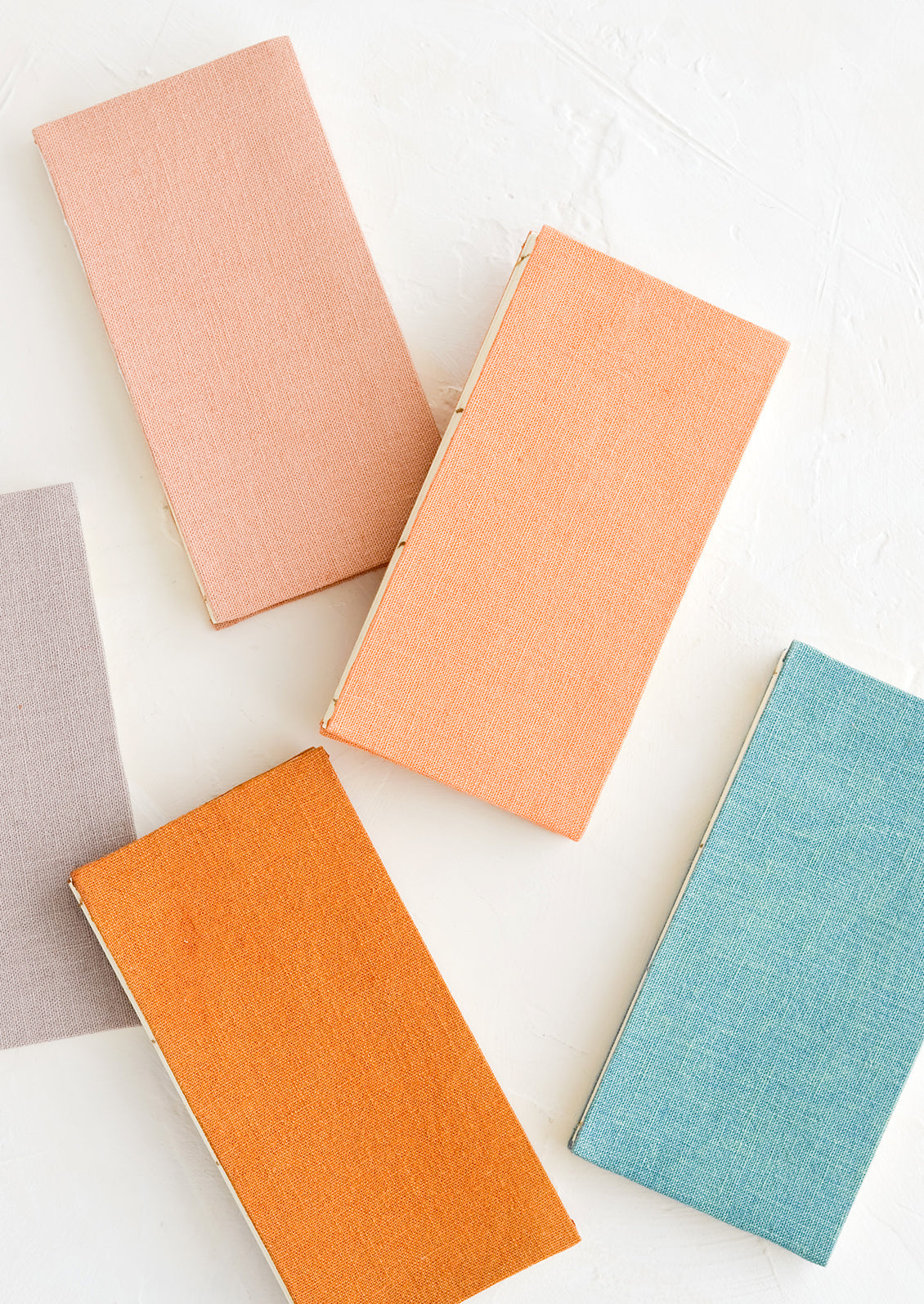 Five cloth-covered notebooks in naturally dyed hues.