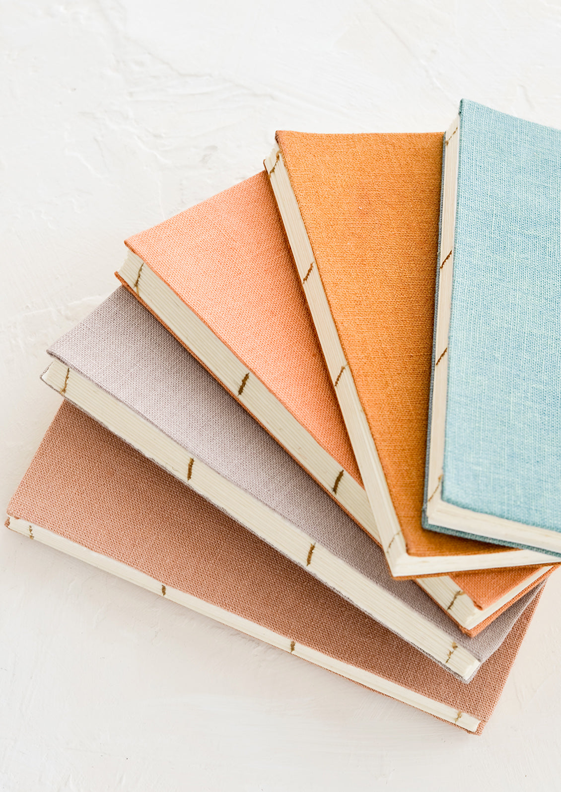 Five cloth-covered notebooks with hand bound pages in naturally dyed hues.