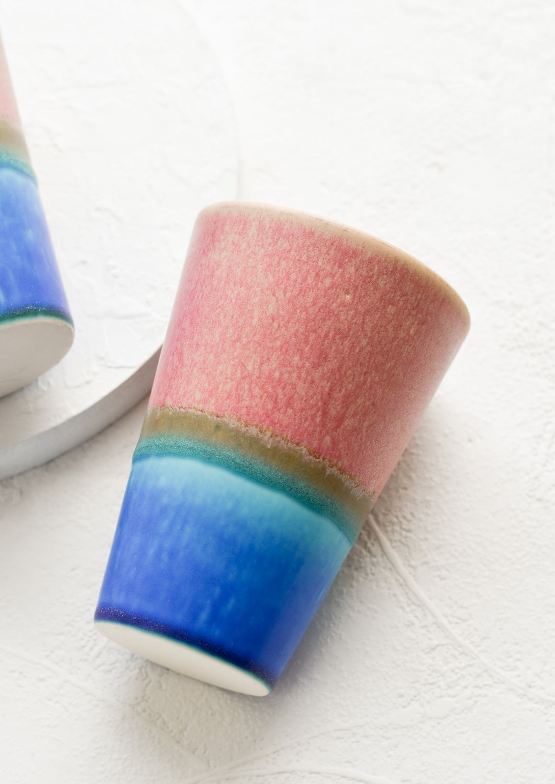 A ceramic cup in pink and blue.