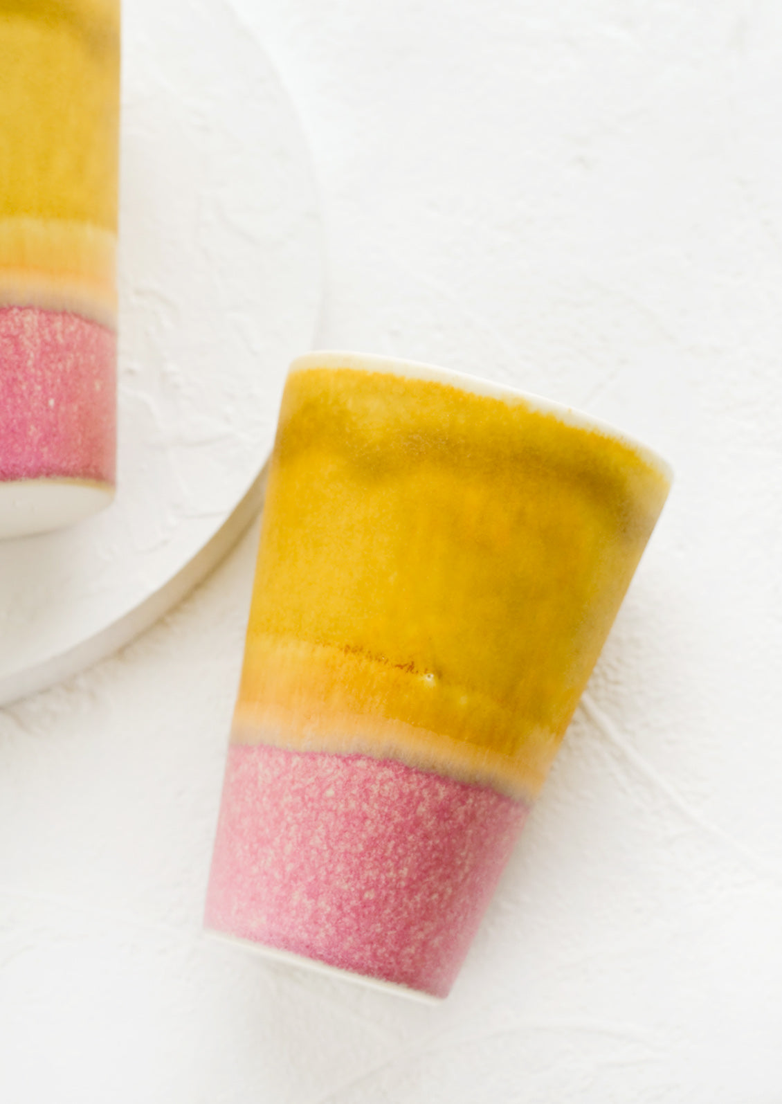 A ceramic cup in yellow and pink.