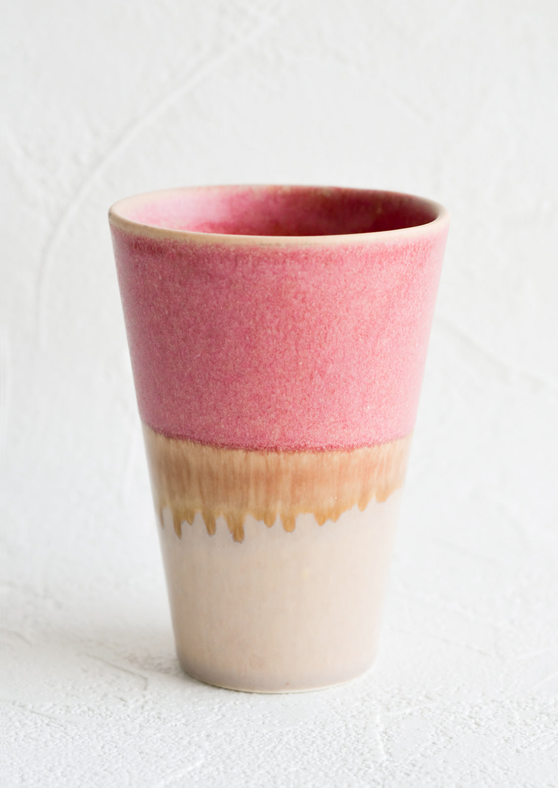 A ceramic cup in pink and brown.