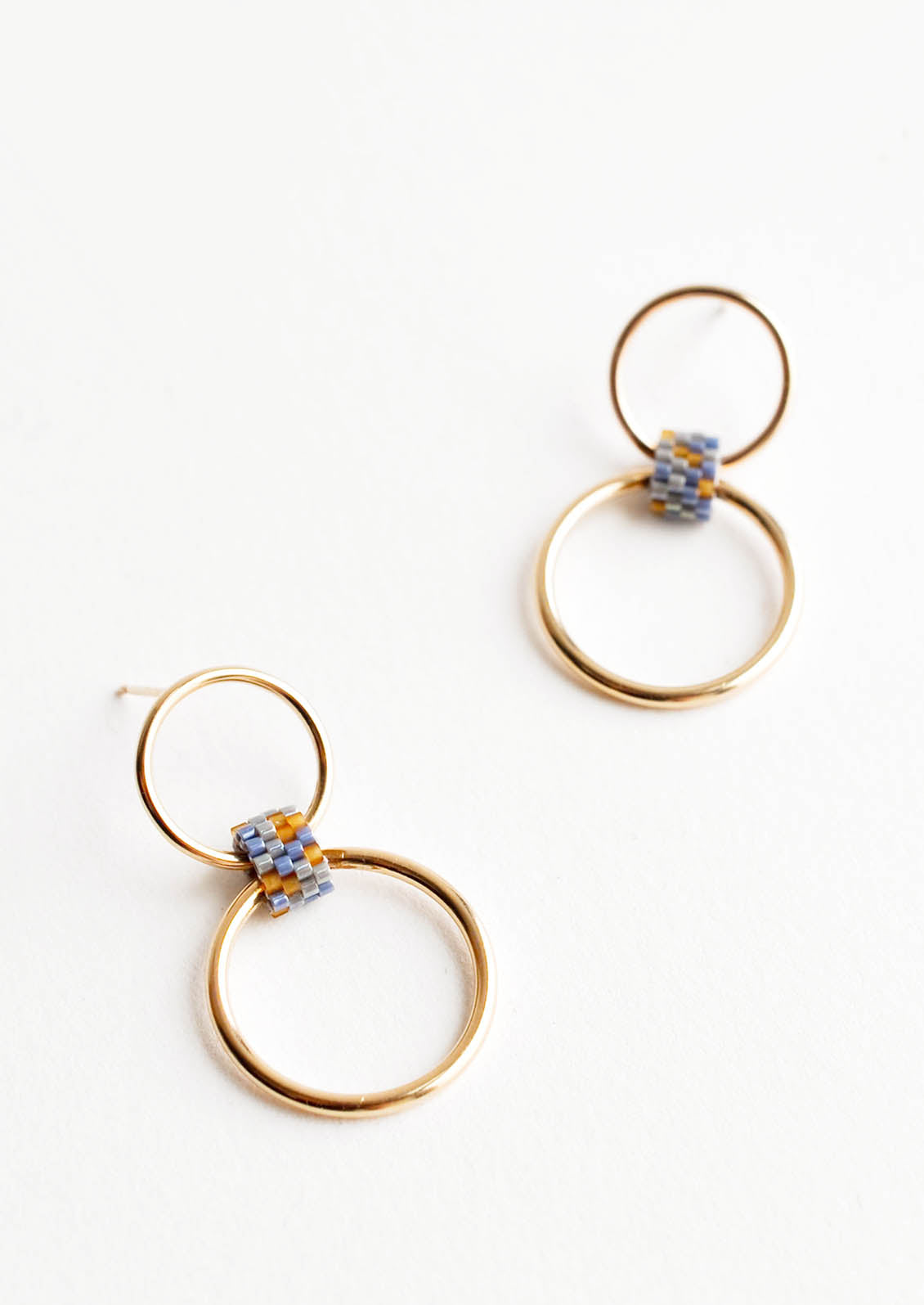 Post back earrings of one small hoop and one larger hoop connected by a loop of blue-gray glass beads.