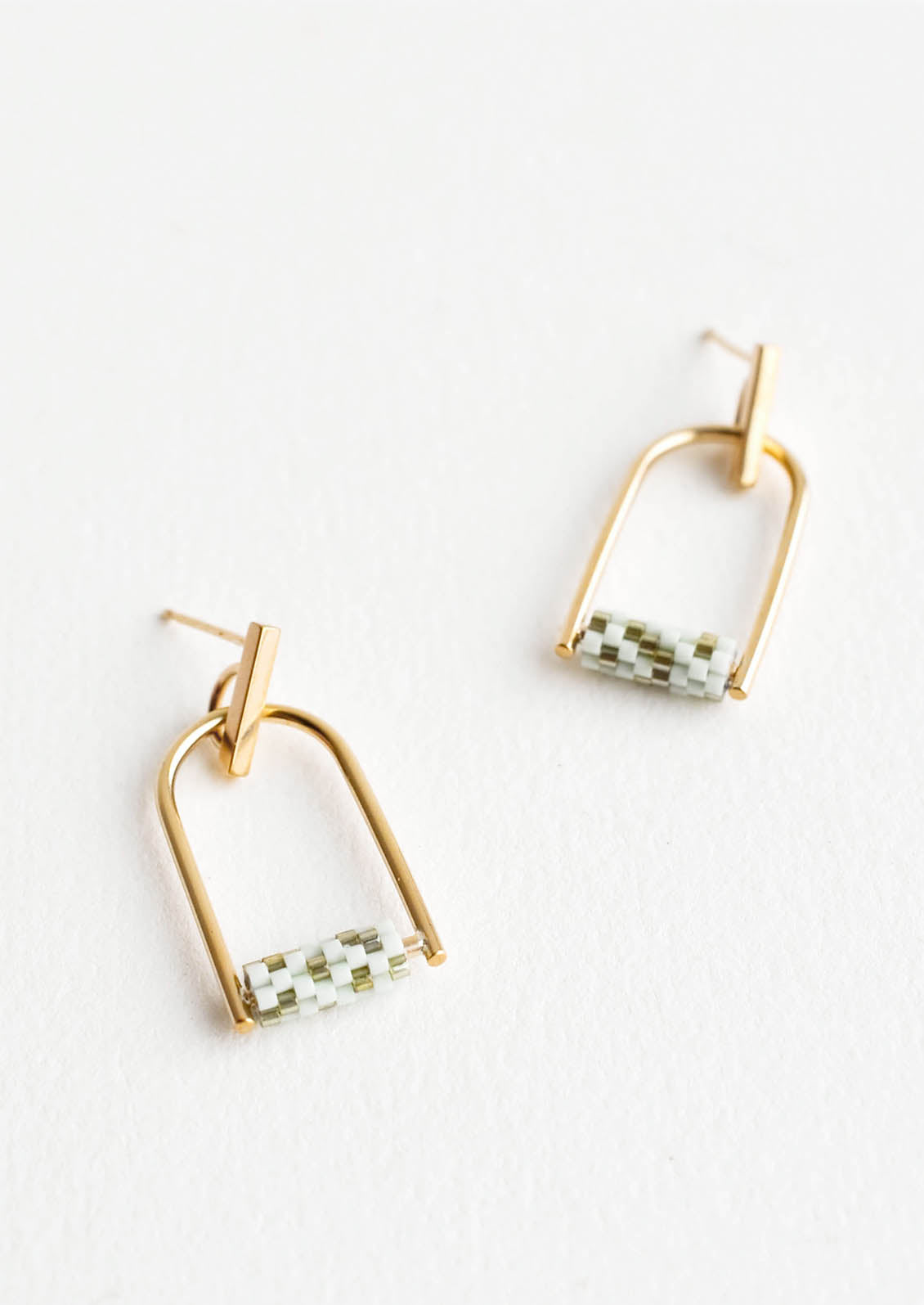 Arced gold post back earrings with mint and olive green beads closing off the arc.