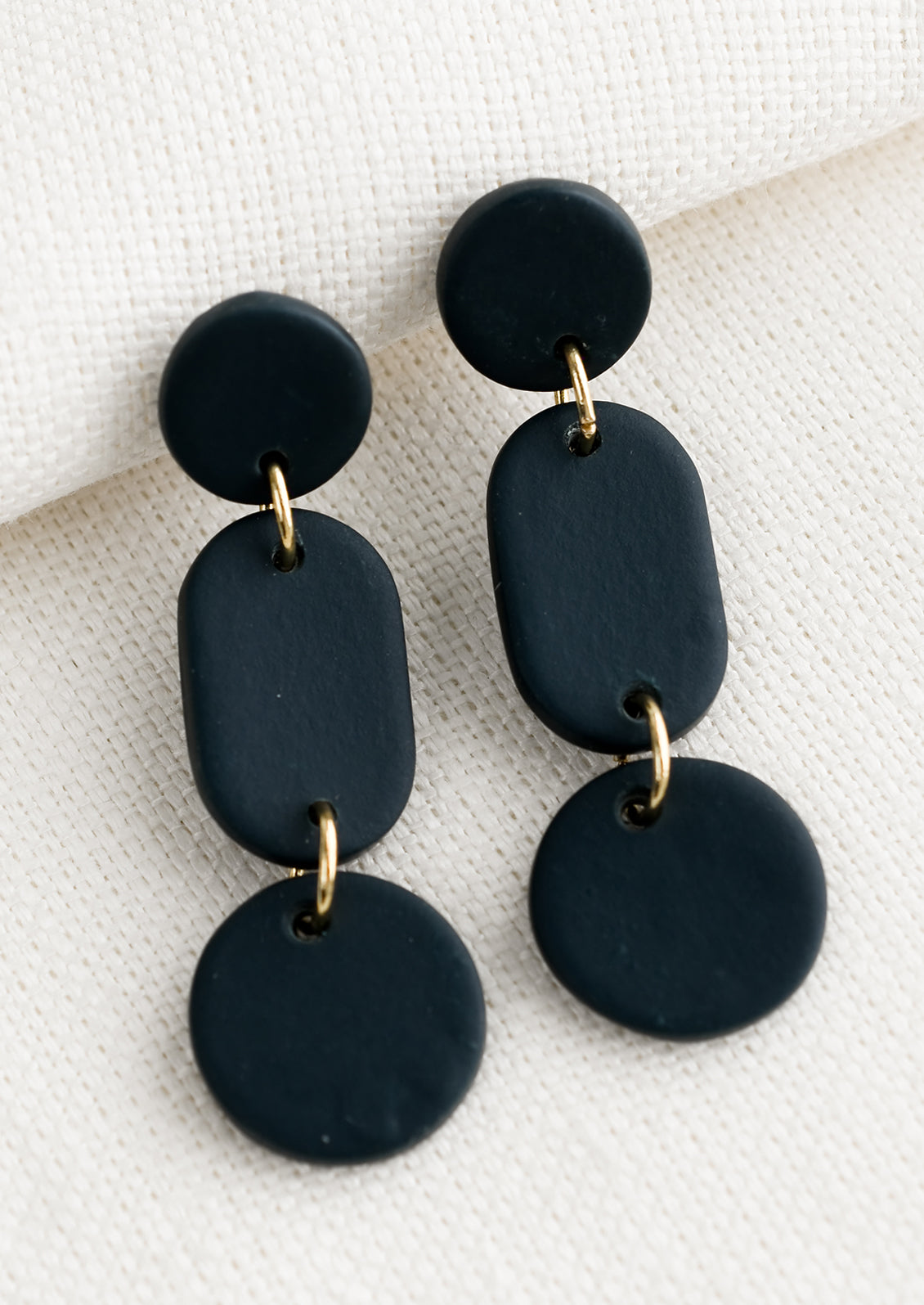 A pair of earrings in three part geometric design in midnight blue.