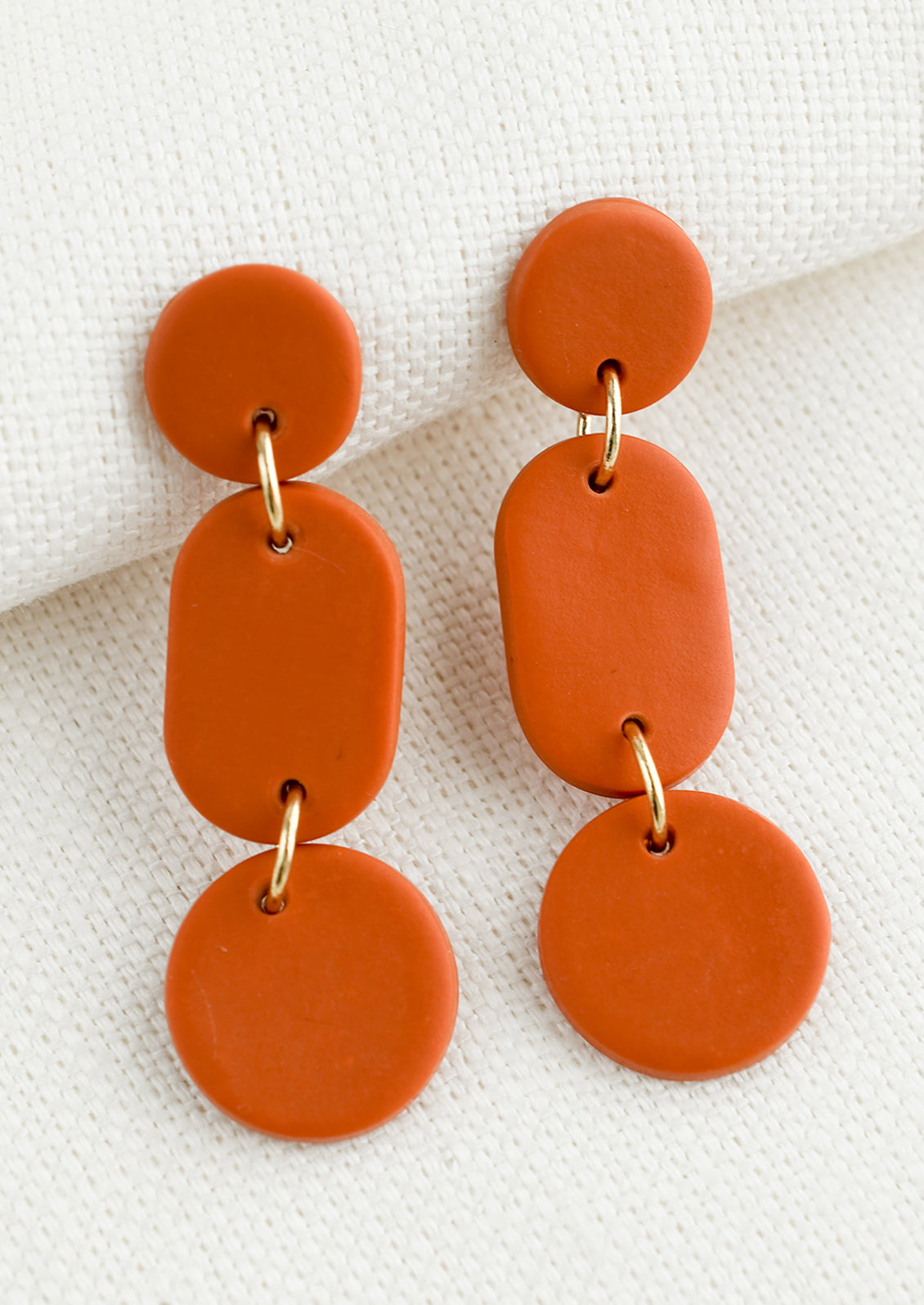 A pair of earrings in three part geometric design in persimmon.
