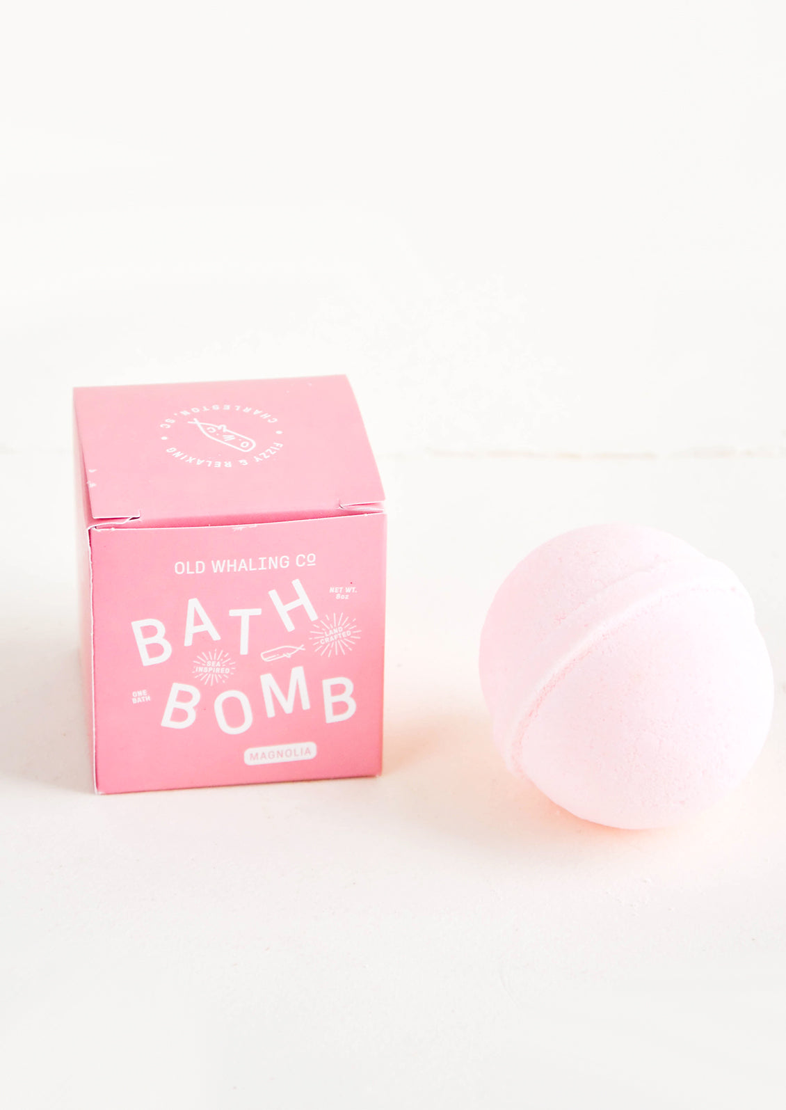 Pink colored, round bath bomb with pink boxed packaging