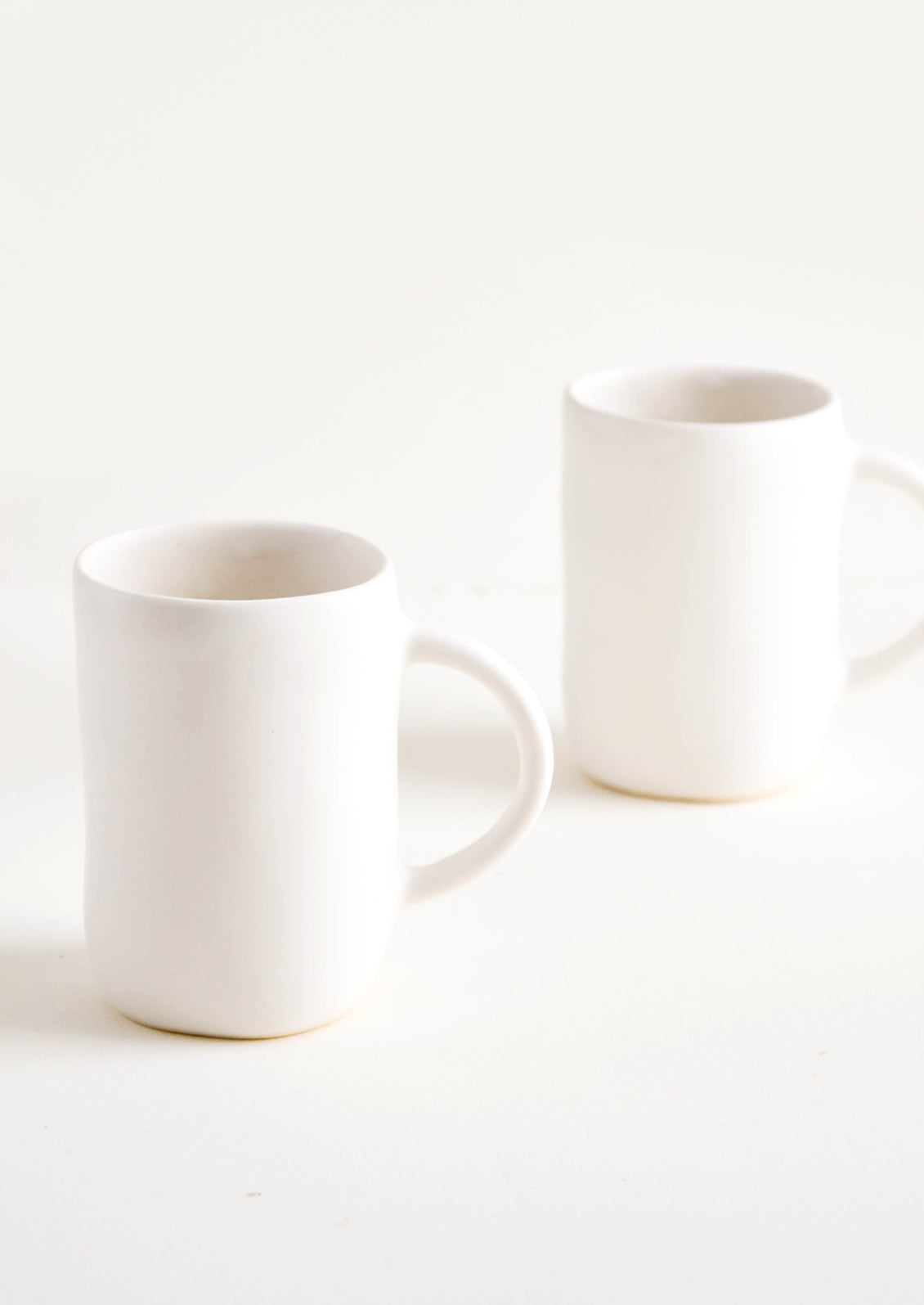 Ceramic mugs with handle in matte white glaze.