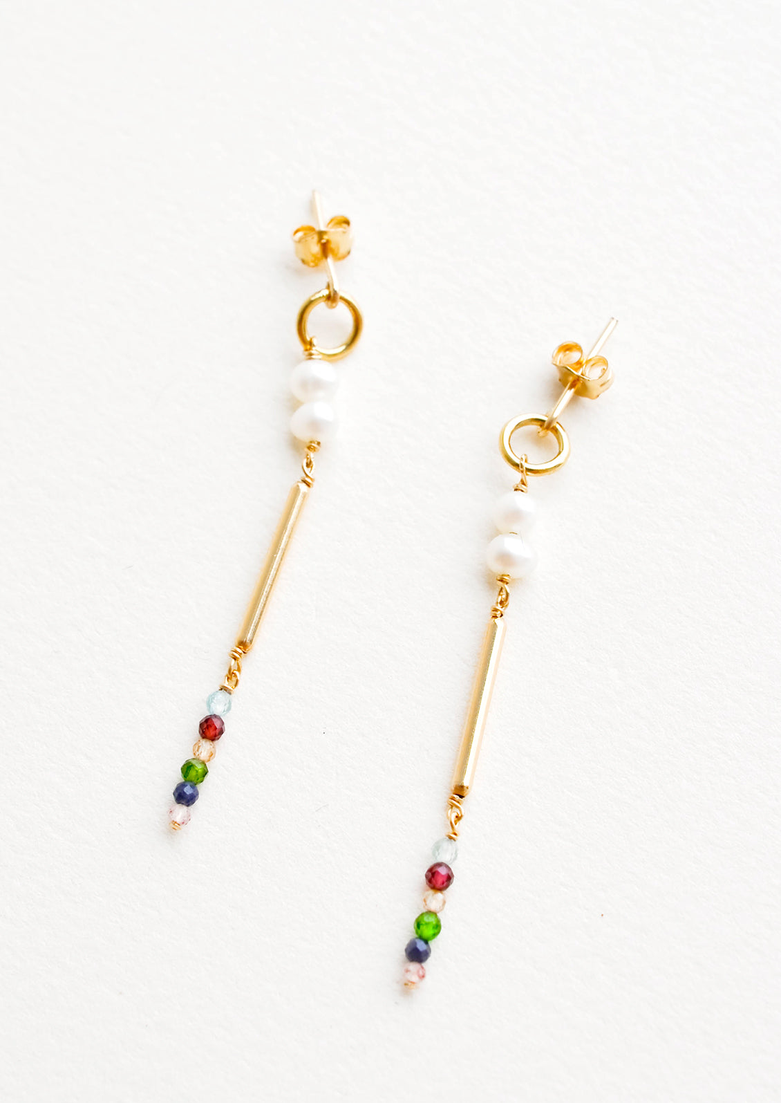 Dangling earrings featuring a small circle, two pearl beads, a gold post and six small multicolor gemstones on a yellow gold post back.