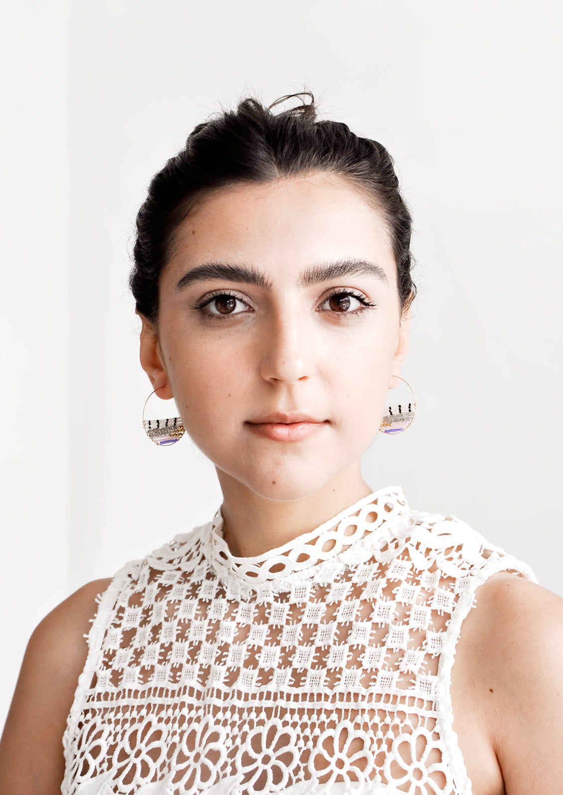 Model shown wearing earrings and white top.