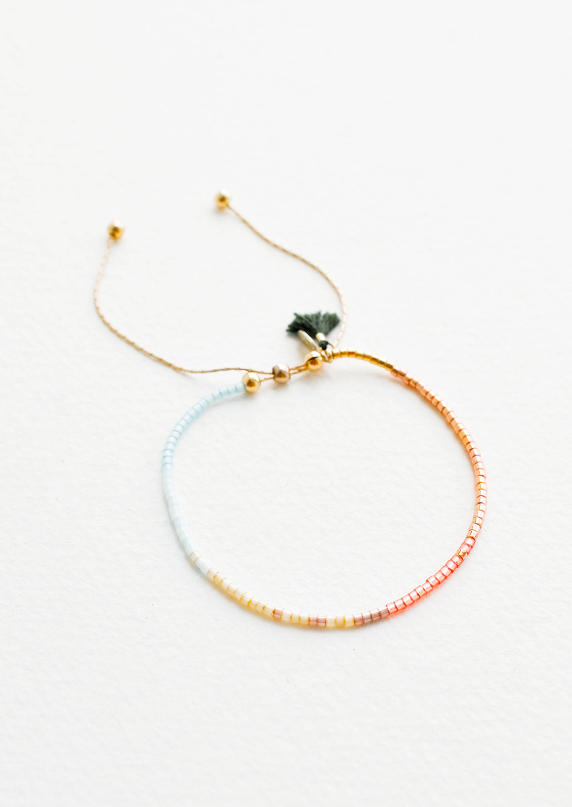 Delicate bracelet of glass beads in a gradient from pale blue to deep rust on a thin gold chain.