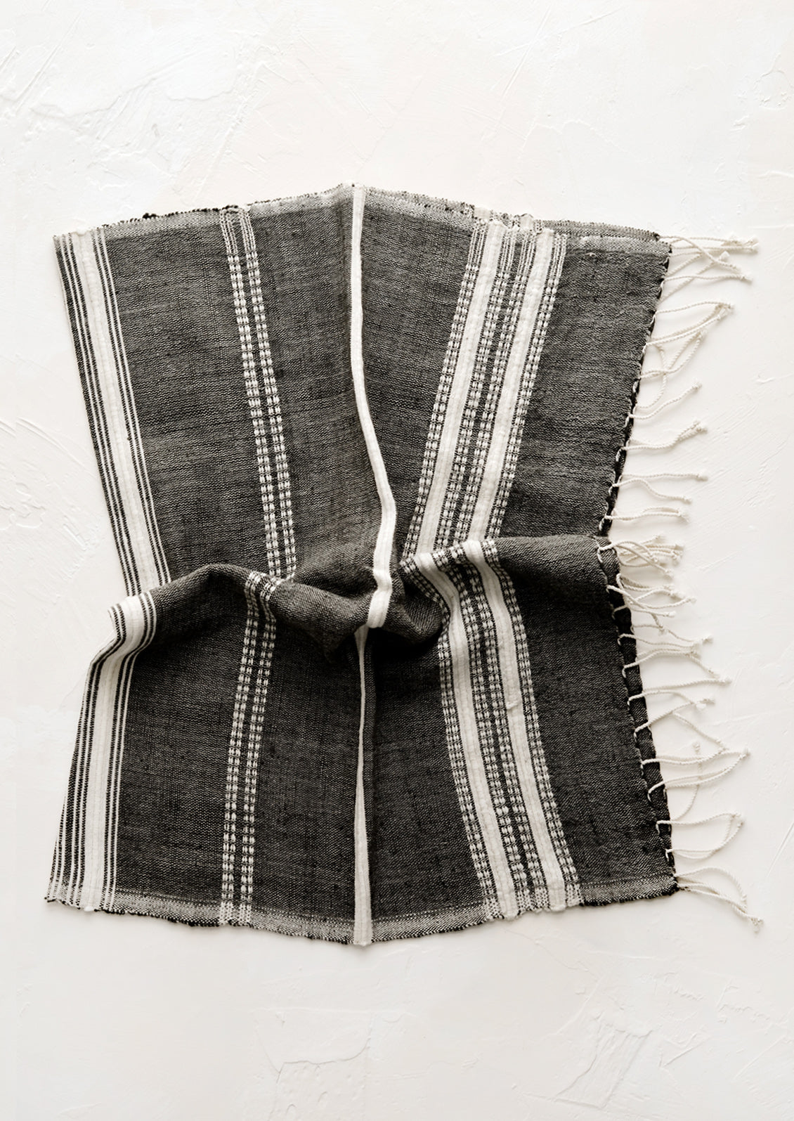 A cotton hand towel in black with woven natural stripes.