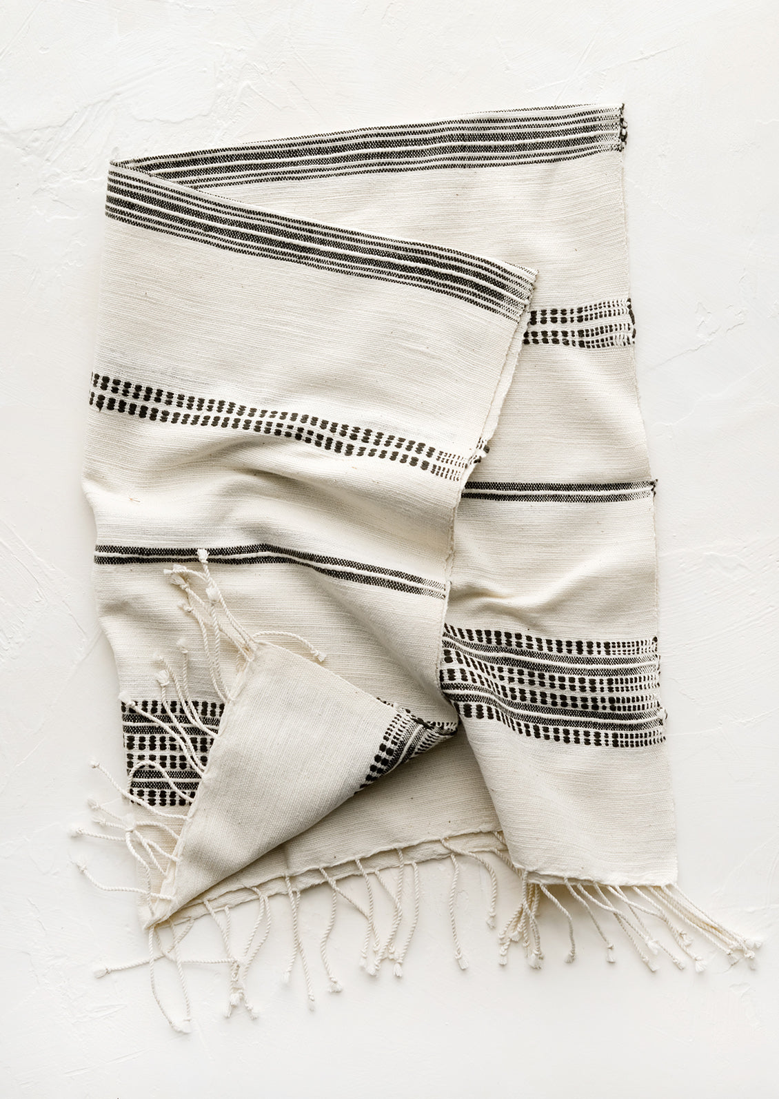 A cotton hand towel in natural with woven black stripes.