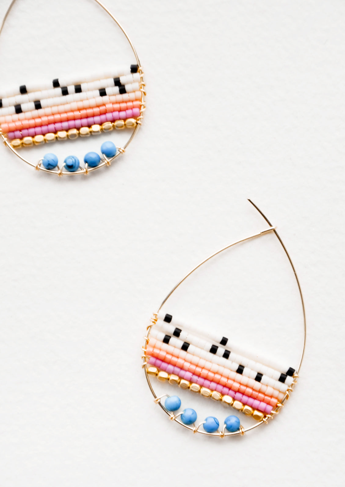 Teardrop shaped hoop earrings in yellow gold with multicolored ivory and turquoise beaded bars across. 