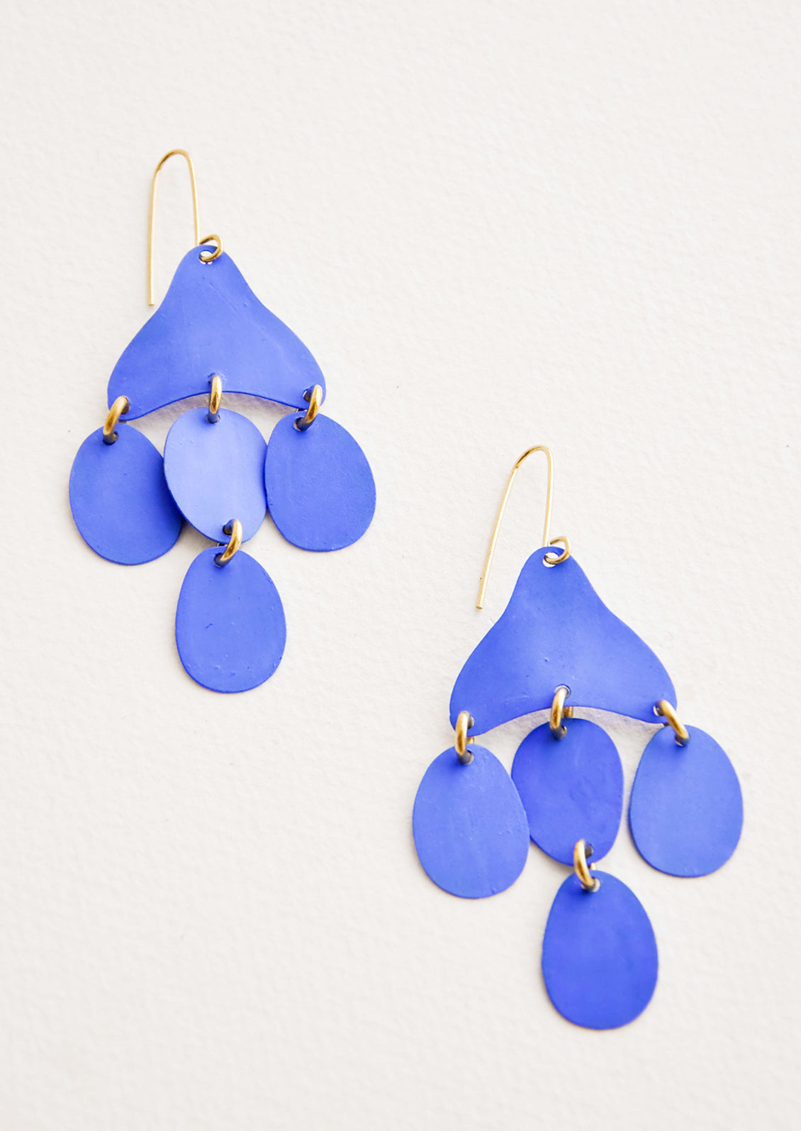 Dangling earrings featuring 4 oval shape charms in matte bright blue metal hanging from an asymmetric triangle in the same color.