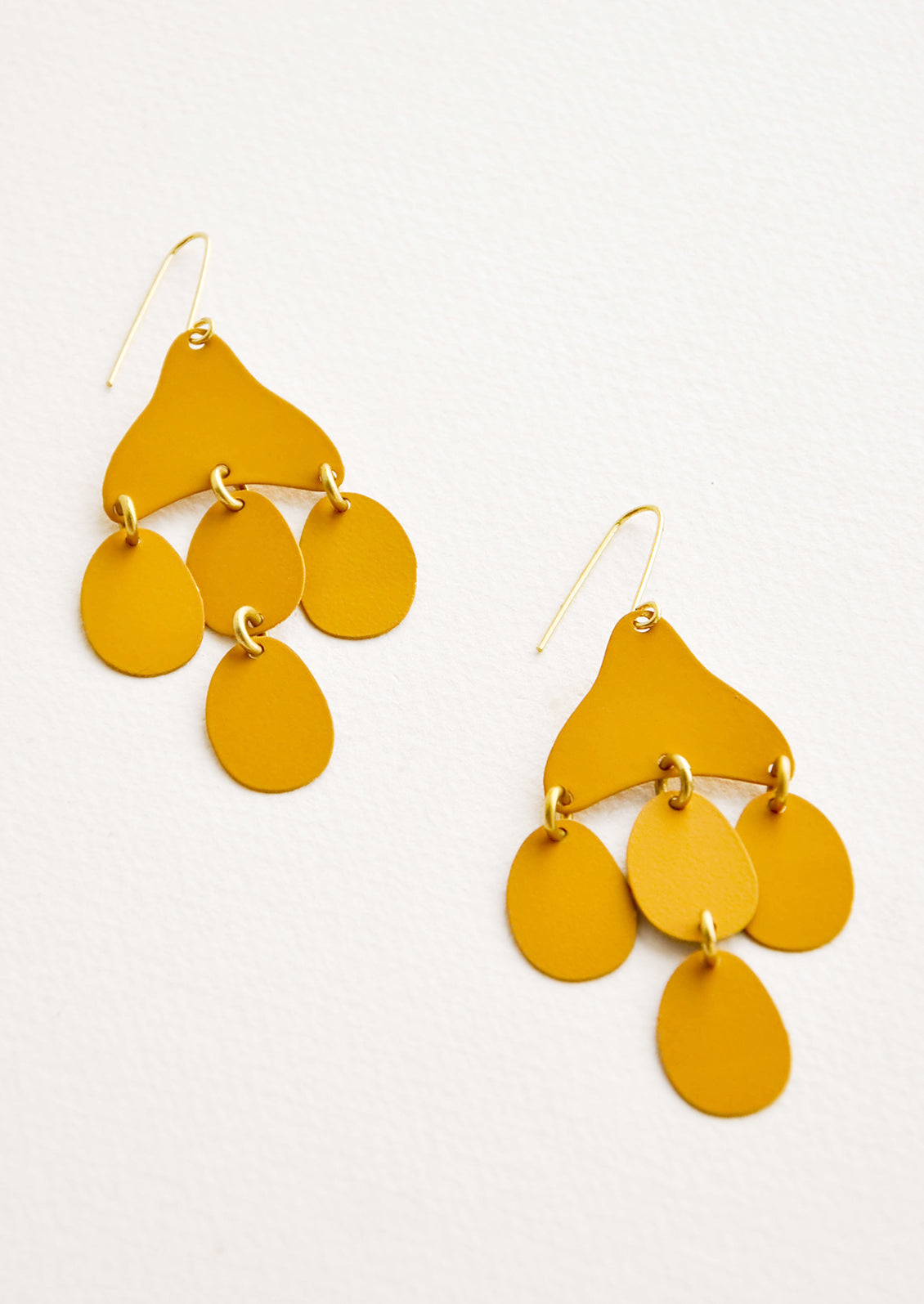 Dangling earrings featuring 4 oval shape charms in matte dark yellow metal hanging from an asymmetric triangle in the same color.