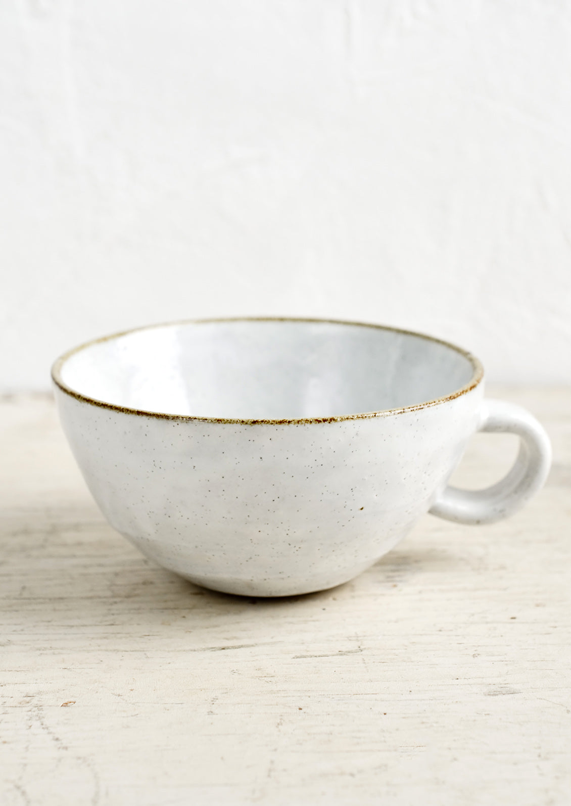 A ceramic latte mug in a glossy white glaze with soft speckles.
