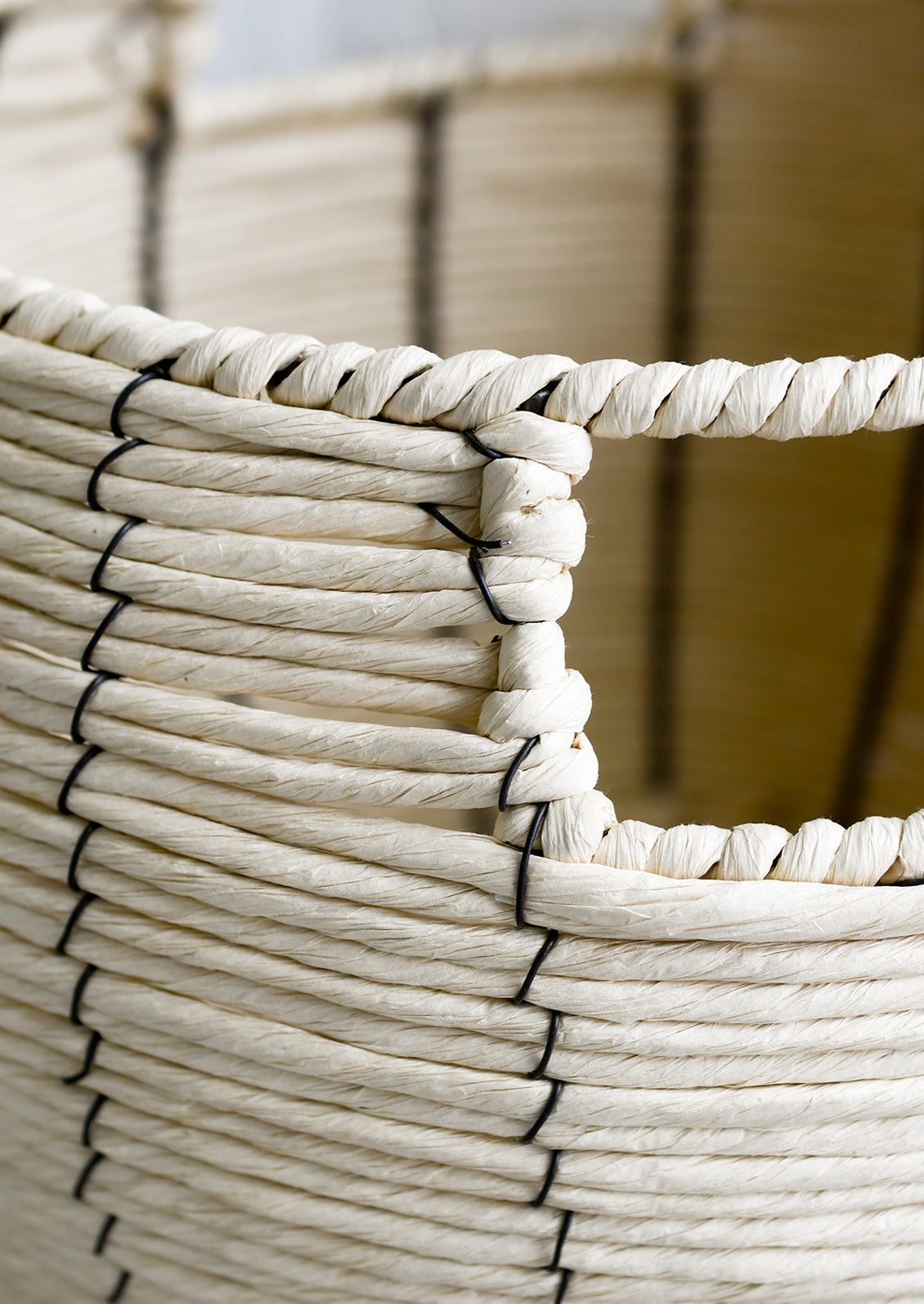 A round belly shaped basket in natural cord with thin black vertical stripe.