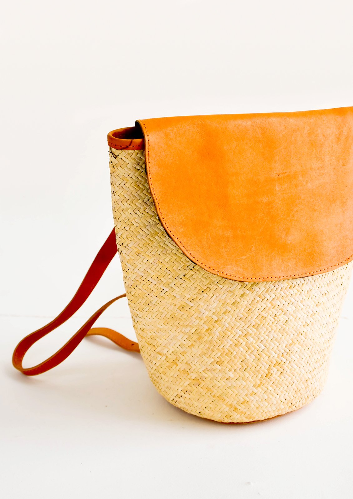 Woven straw backpack with leather trim and curved front flap
