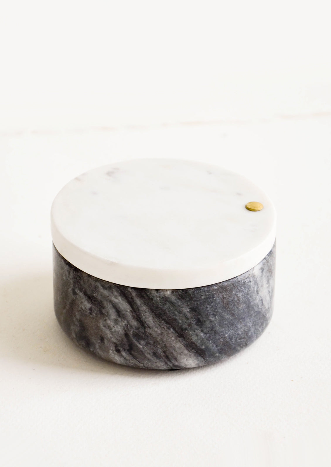 Round salt cellar made of black marble with white marble lid