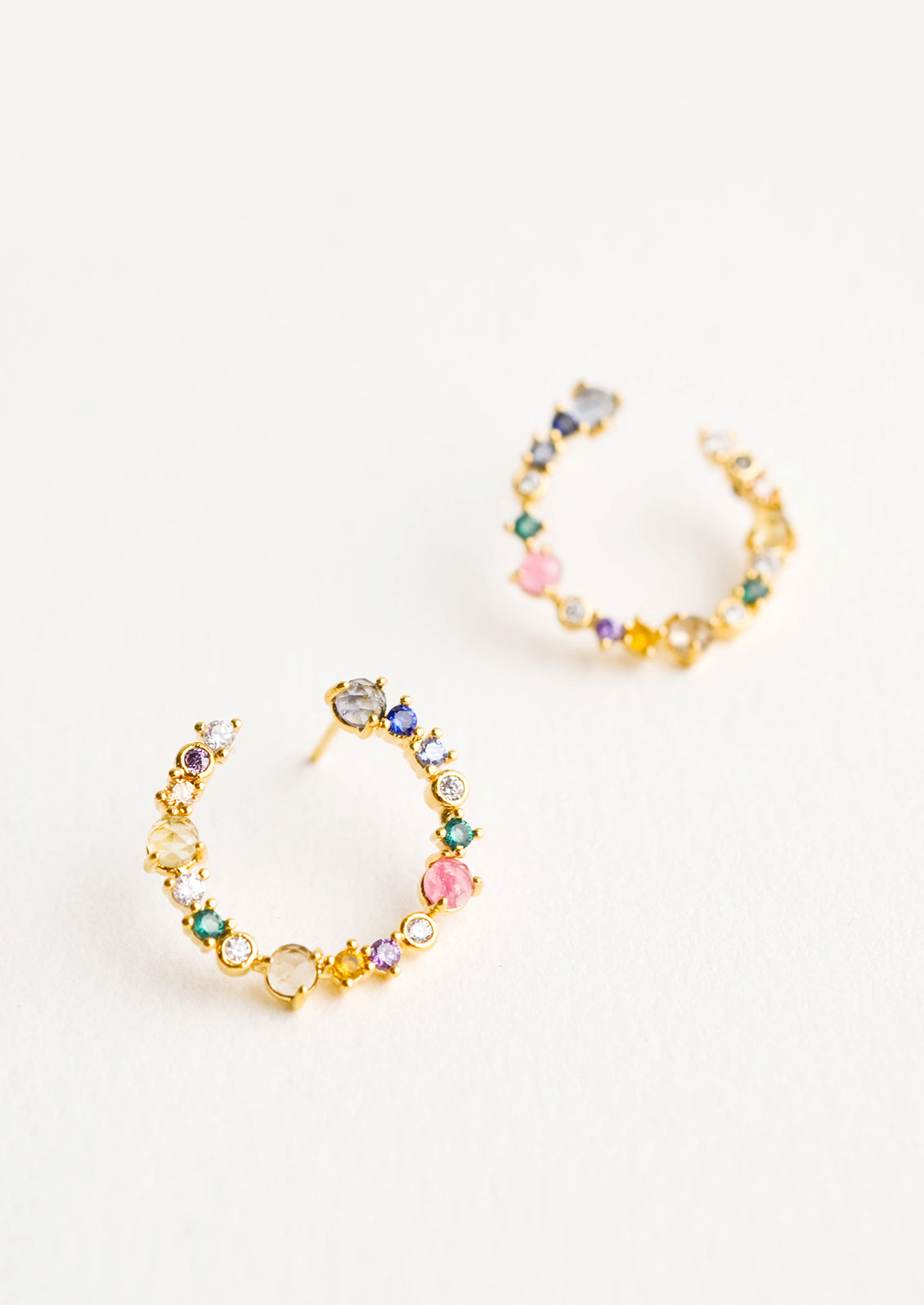 Curved, hoop-like earrings in colored crystals in a mix of sizes and shapes
