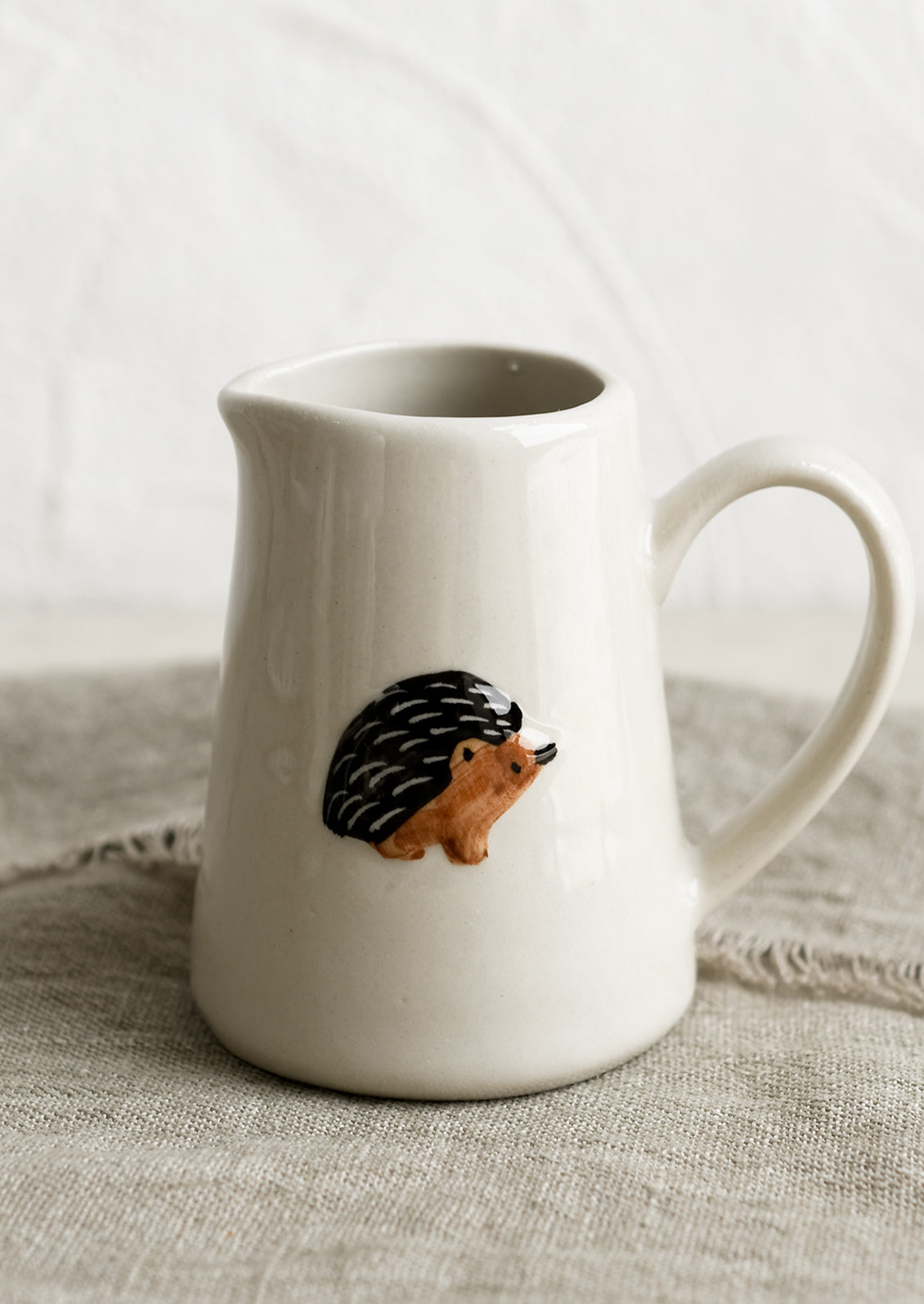 A small creamer pitcher in natural ivory with porcupine motif.